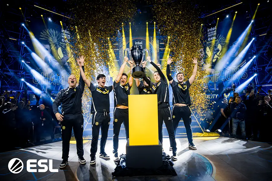 Esports team viert op het podium met een trofee en confetti tijdens een ESL kampioenschap.